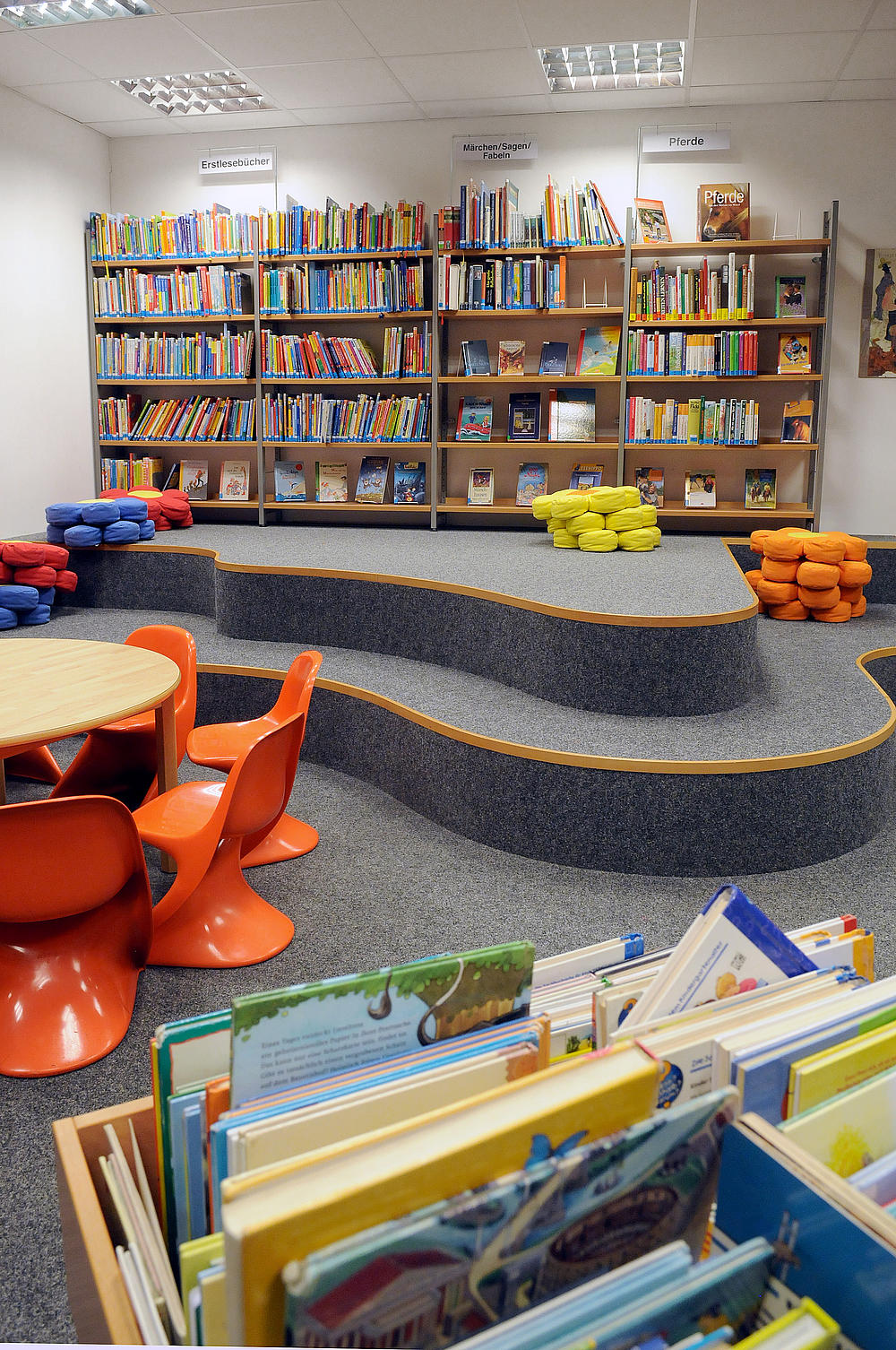 Modernes Podest zum Hinsetzen, Spielen und Lesen in der Bücherei Rellingen.